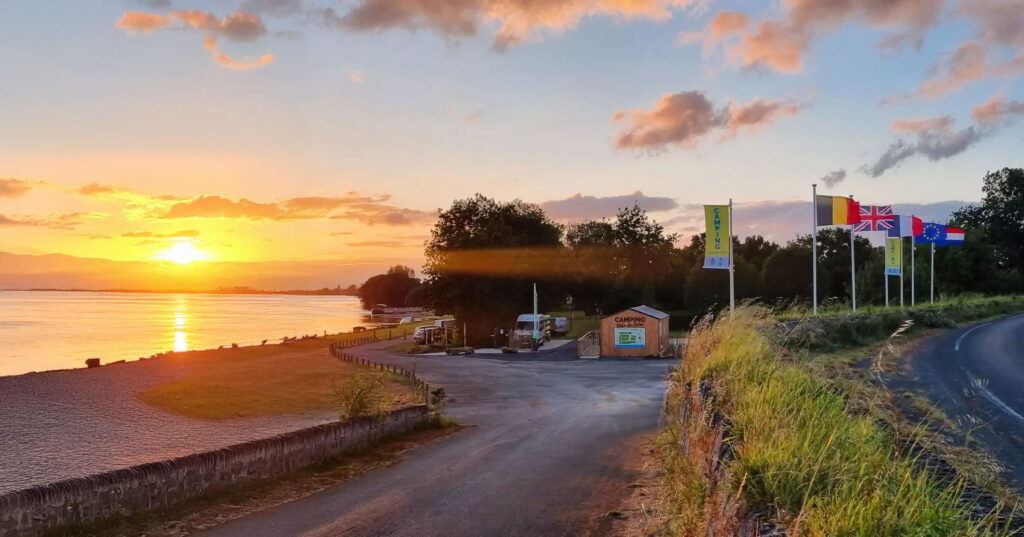 Entrée du camping en bord de Loire au coucher de soleil, avec drapeaux et route